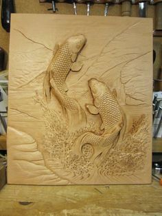 a wood carving of two fish in the water