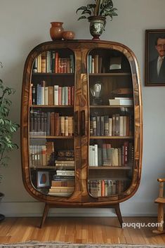 a bookcase with many books on it in front of a painting and potted plant