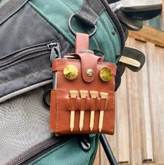 a brown leather case sitting on top of a green and gray backpack with two knives sticking out of it