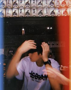 a man is holding his hands up to his head in front of a wall full of beer bottles