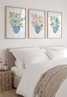 three paintings on the wall above a bed with white sheets and pillows in a bedroom