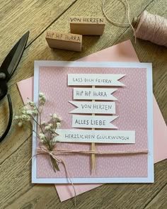 a pink card with some words on it next to scissors and thread spools