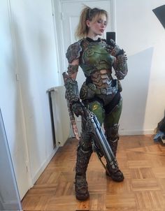 a woman dressed in armor and holding a bike on a hard wood flooring area