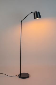 a black floor lamp with a white light on the side and a gray shade over it