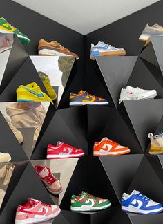 many different colored shoes are on display in front of a black and white geometric wall