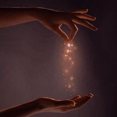 two hands reaching out towards each other to light up sparkles in the dark sky