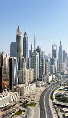 an aerial view of a city with skyscrapers and cars on the road in front of it