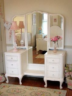 a white dresser and mirror in a room with pink flowers on the floor next to it