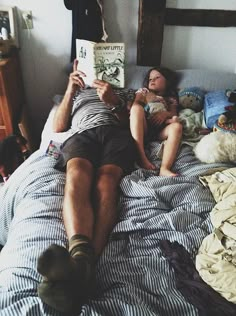 a man laying in bed reading a book