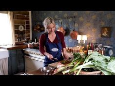 a woman standing in a kitchen preparing food on top of a wooden cutting board next to a potted plant