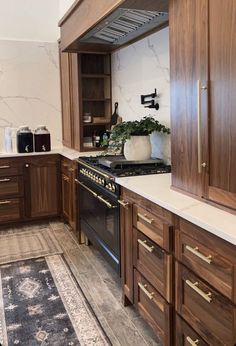 a kitchen with wooden cabinets and marble counter tops, including an oven hood over the stove