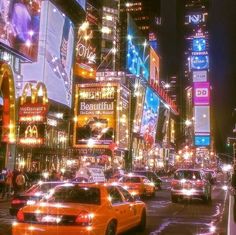 a city street filled with lots of tall buildings and traffic lights at night in times square