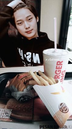 a person sitting at a table with a drink and some food in front of them