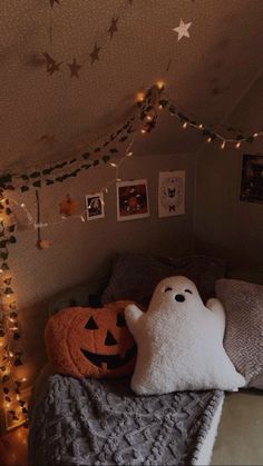 there is a bed with two pumpkins on it and lights strung from the ceiling