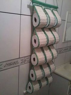 several rolls of toilet paper hanging on a wall in a bathroom with white tiles and green trim