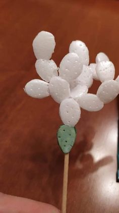 a person holding a toothpick with some white flowers on it and a cell phone in the background