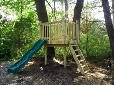 a tree house with a slide in the woods