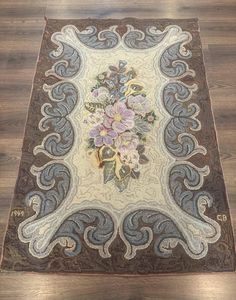 an area rug with flowers and swirls on the floor in front of a wooden floor