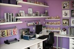 a home office with purple walls and white shelves