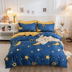 a bed with yellow and blue stars on it, next to a night sky print comforter set