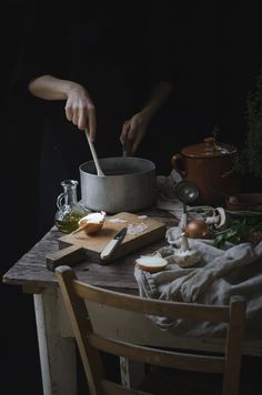 a person is cooking in a pot on a table with other food items and utensils