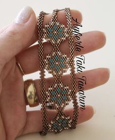 a hand holding a beaded bracelet and ring