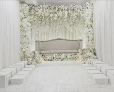 a white wedding setup with flowers and candles on the floor, along with an elegant couch