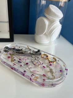 a glass tray with rings on it next to a vase