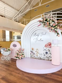 a pink and white stage set up for a baby's first birthday with flowers on it