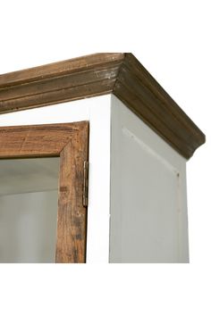 an old wooden cabinet with glass doors on the top and bottom half, against a white wall