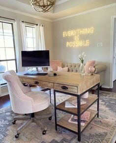 a desk with a computer on it in front of a window and a chair next to it