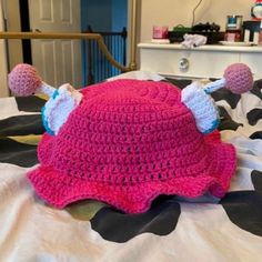 a pink crocheted hat with ears on top of a bed