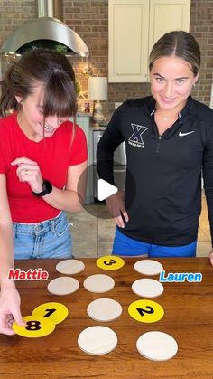 two young women standing next to each other near a wooden table with numbers on it