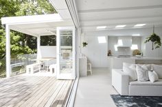 a white couch sitting on top of a wooden floor next to a living room filled with furniture