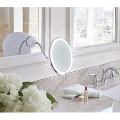 a bathroom sink with a mirror above it and flowers on the counter next to it