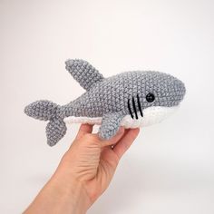 a hand is holding a stuffed shark toy