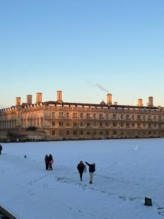 some people are walking in the snow near a building