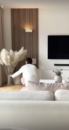 a person sitting on a couch in front of a flat screen tv and holding some flowers