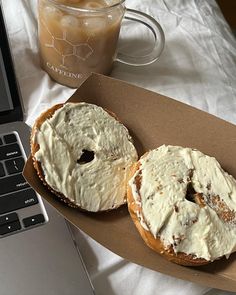 two bagels sitting on top of a table next to a cup of coffee and a laptop