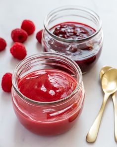 raspberry jam in two jars with spoons on the side