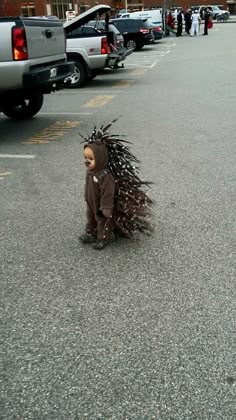 a small child in a costume is walking down the street with feathers on his head