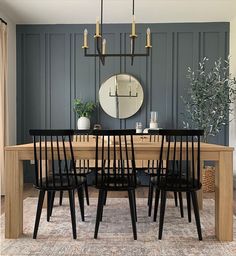 a dining room table with six chairs and a round mirror on the wall above it