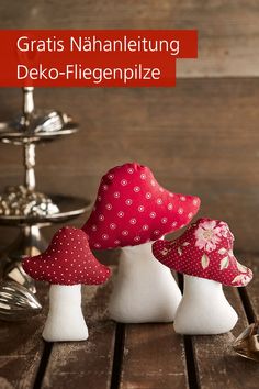 three small white and pink mushrooms sitting on top of a wooden table next to each other