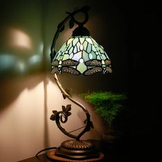 a table lamp sitting on top of a wooden table next to a potted plant