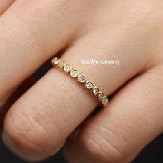 a woman's hand wearing a gold ring with small diamonds on the middle finger