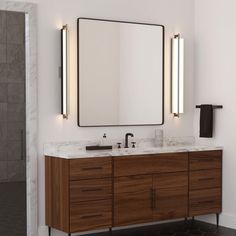 a bathroom vanity with two mirrors and lights on the wall, along with a large mirror above it