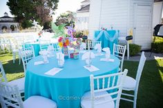 a table set up for a party with blue and white tables cloths, chairs and centerpieces