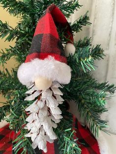 a christmas decoration made out of pine cones and plaid fabric with a gnome's hat on top