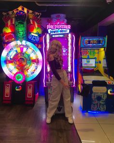 a woman is standing in front of some slot machines and playing video games on the floor