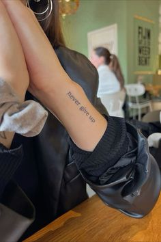 a woman with a tattoo on her arm sitting at a table